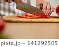 Hands slicing fresh red bell pepper on wooden board 141292505