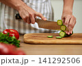 Woman slicing fresh cucumber for healthy cooking 141292506