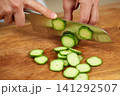 Chef hands slicing fresh cucumber on cutting board 141292507