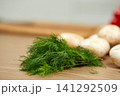 Fresh green dill bunch and mushrooms on wooden surface 141292509
