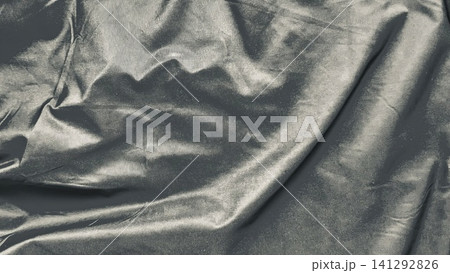 shimmering gunmetal satin fabric creates elegant liquid ripples across dramatic minimalist textile backdrop 141292826