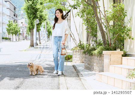新緑の並木道で愛犬と散歩する笑顔の若い女性 新緑の並木道で愛犬と散歩する笑顔の若い女性 141293507