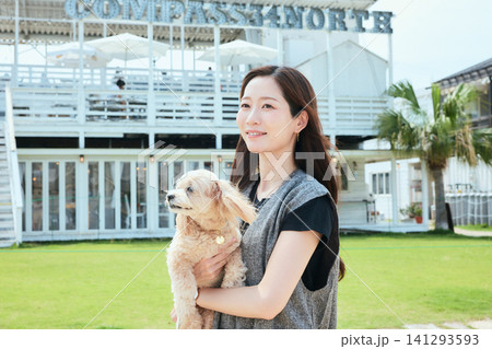 海辺のカフェの芝生で愛犬を抱く笑顔の女性 海辺のカフェの芝生で愛犬を抱く笑顔の女性 141293593