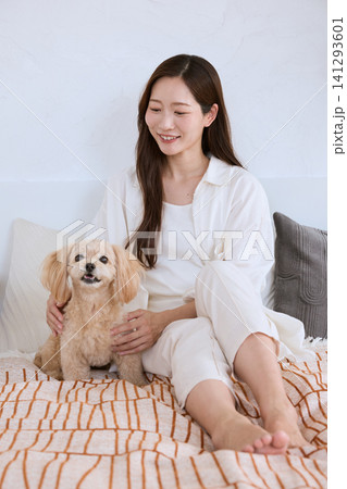 ソファで愛犬のトイプードルを抱きしめる笑顔の若い女性 ソファで愛犬のトイプードルを抱きしめる笑顔の若い女性 141293601