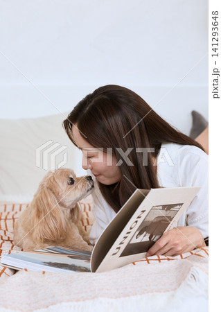 ソファで雑誌を読みながら愛犬と触れ合う若い女性 ソファで雑誌を読みながら愛犬と触れ合う若い女性 141293648
