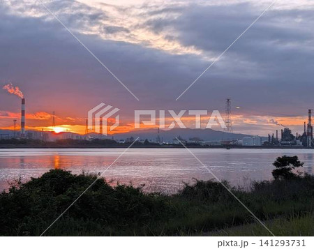 夕焼けに染まる工場地帯と穏やかな水辺の風景 夕焼けに染まる工場地帯と穏やかな水辺の風景 141293731