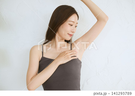 脇を見せて微笑むキャミソール姿の若い女性 脇を見せて微笑むキャミソール姿の若い女性 141293789