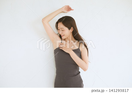 脇を見せて微笑むキャミソール姿の若い女性 脇を見せて微笑むキャミソール姿の若い女性 141293817