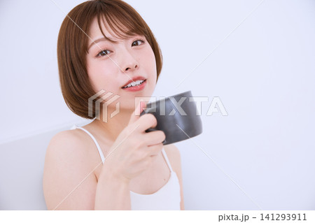 マグカップを持ちながら微笑む若い女性のリラックスタイム マグカップを持ちながら微笑む若い女性のリラックスタイム 141293911
