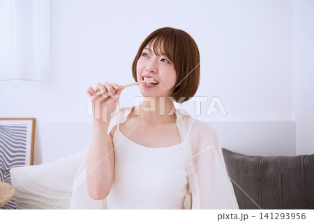 リビングで歯磨きをする笑顔の若い女性 141293956