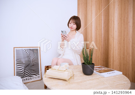 おしゃれな部屋でスマートフォンを見る若い女性 おしゃれな部屋でスマートフォンを見る若い女性 141293964