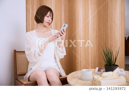 カフェでスマートフォンを操作するボブヘアの若い女性 カフェでスマートフォンを操作するボブヘアの若い女性 141293972