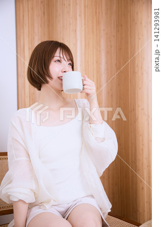 白い服を着てコーヒーカップを持つ短髪の若い女性 白い服を着てコーヒーカップを持つ短髪の若い女性 141293981