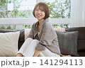 ソファに座って笑顔を見せるショートヘアの若い女性 141294113