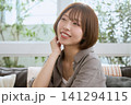カフェのソファに座り笑顔でくつろぐショートボブの若い女性 141294115