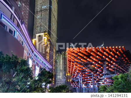 the Chongqing Guotai Arts Center (also known as the Chongqing Art Museum or "Chopsticks Building") showcasing its iconic red interwoven structural facade, illuminated against the downtown skyline in the Chongqing Guotai Arts Center (also known as the Chongqing Art Museum or "Chopsticks Building") showcasing its iconic red interwoven structural facade, illuminated against the downtown skyline in 141294131