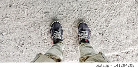 Top-down view of shoes and trousers on a concrete floor 141294209