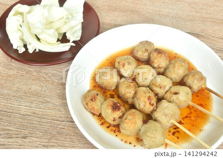 grilled beef tendon meatball stabbing in wooden stick dressing spicy and sweet tamarind sauce on plate with fresh cabbage salad grilled beef tendon meatball stabbing in wooden stick dressing spicy and sweet tamarind sauce on plate with fresh cabbage salad 141294242