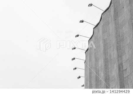 Concrete old building architecture structure cement facade apartment stone with elements of illumination bulbs on the roof against a background of gray sky Concrete old building architecture structure cement facade apartment stone with elements of illumination bulbs on the roof against a background of gray sky 141294429