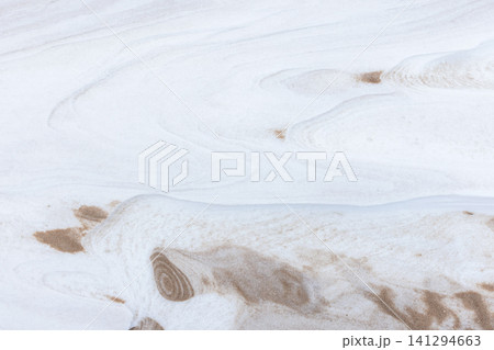 Soft white snowdrift with sand creates delicate ripple patterns Soft white snowdrift with sand creates delicate ripple patterns 141294663