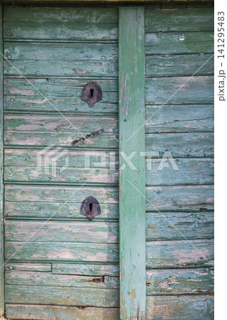 Weathered green wooden door showing ancient keyholes 141295483