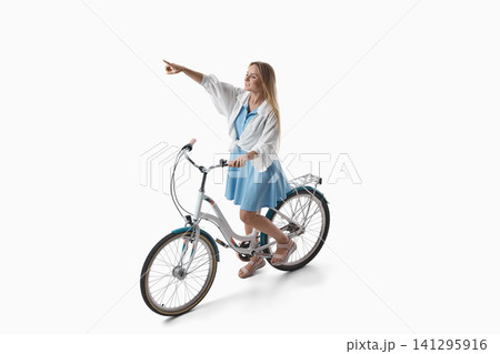 Woman pointing ahead while seated on bicycle on white background. 141295916