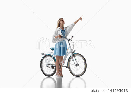 Woman pointing upward beside bicycle on white background Woman pointing upward beside bicycle on white background 141295918