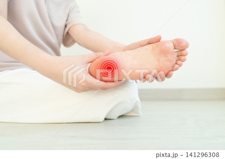 Woman suffering from foot pain. Causes of foot heel pain include plantar fasciitis, tendonitis, sprains, bursitis and osteoarthritis. Close up. Woman suffering from foot pain. Causes of foot heel pain include plantar fasciitis, tendonitis, sprains, bursitis and osteoarthritis. Close up. 141296308