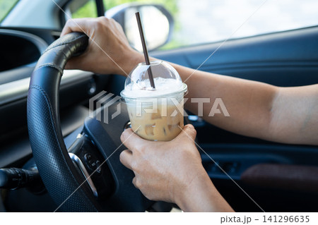 Asian lady driver holding ice coffee in car. Asian lady driver holding ice coffee in car. 141296635