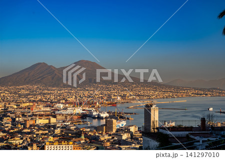 Naples, italy. December 28, 2024. Naples city view with vesuvius volcano, port activities, and urban landscape at sunset on the bay of naples Naples, italy. December 28, 2024. Naples city view with vesuvius volcano, port activities, and urban landscape at sunset on the bay of naples 141297010