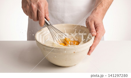 Person whisking eggs in a ceramic bowl creating a splash on a white kitchen workspace with whisking preparation culinary breakfast ingredient whipping movement energetic minimalist gastronomy Person whisking eggs in a ceramic bowl creating a splash on a white kitchen workspace with whisking preparation culinary breakfast ingredient whipping movement energetic minimalist gastronomy 141297280