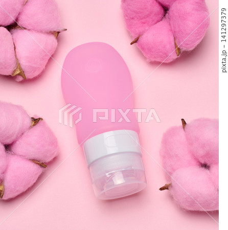 Pink travel cosmetic bottle lie surrounded by soft cotton flowers Pink travel cosmetic bottle lie surrounded by soft cotton flowers 141297379
