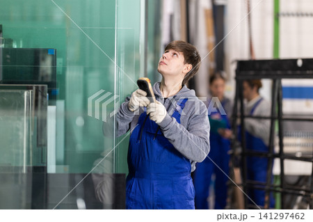Young man employee in blue overall uses remote control to move lifting mechanism 141297462