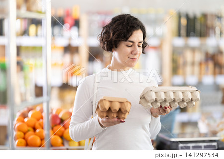 In store, woman near counter are looking at varieties of eggs In store, woman near counter are looking at varieties of eggs 141297534