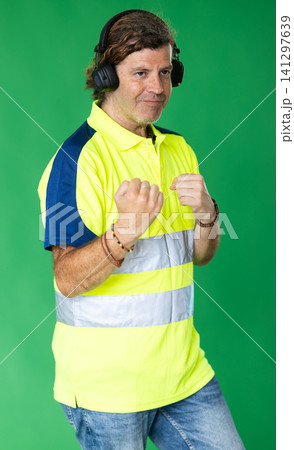 Employee in special clothing stands in headphones on a green background 141297639