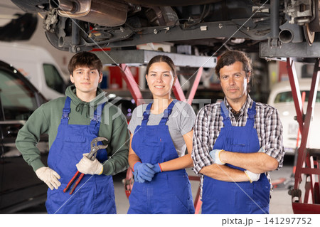 Professional team of auto repair shop posing next to hydraulic lift Professional team of auto repair shop posing next to hydraulic lift 141297752