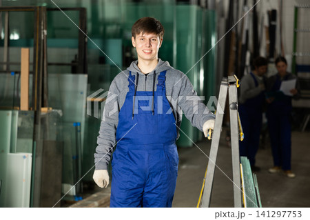 Guy glazer employee in blue overall works in glass processing shop 141297753