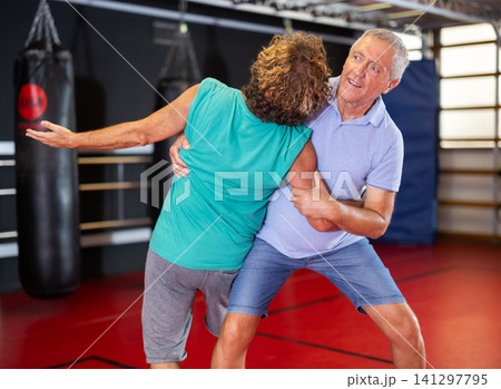 Focused senior man grappling in amateur wrestling session Focused senior man grappling in amateur wrestling session 141297795