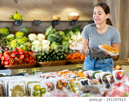 Woman picking out packaged papaya and carrots to buy in fruit and vegetables aisle of supermarket Woman picking out packaged papaya and carrots to buy in fruit and vegetables aisle of supermarket 141297913