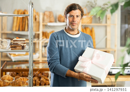 Portrait of an happy man with gift box of fresh baked goods in bakery interior 141297931