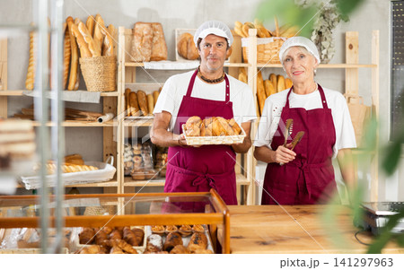 European man and senior woman sellers stands in trading hall of bakery European man and senior woman sellers stands in trading hall of bakery 141297963