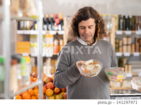 Choose food in supermarket - man chooses poke to buy in the grocery department section of store 141297971