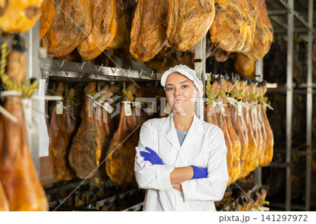 Girl employee in white uniform, bathrobe and hat, stands in workshop for production of hamon 141297972