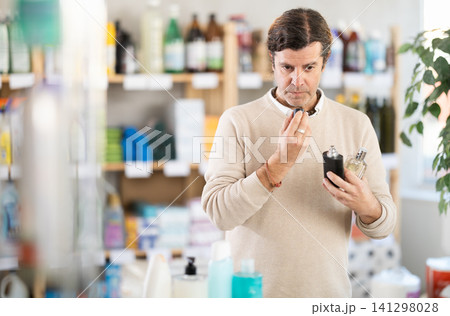 Attentive man chooses perfume or aromatic incense in supermarket Attentive man chooses perfume or aromatic incense in supermarket 141298028