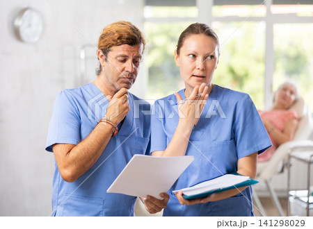 Two fellow doctors discussing clinical diagnosis of patient in clinic Two fellow doctors discussing clinical diagnosis of patient in clinic 141298029