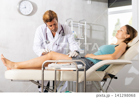 Doctor conducting examination of injured leg and knee of woman 141298068