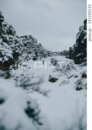 Person hiking through a snowy gorge in Thingvellir National Park, Iceland. Person hiking through a snowy gorge in Thingvellir National Park, Iceland. 141298110