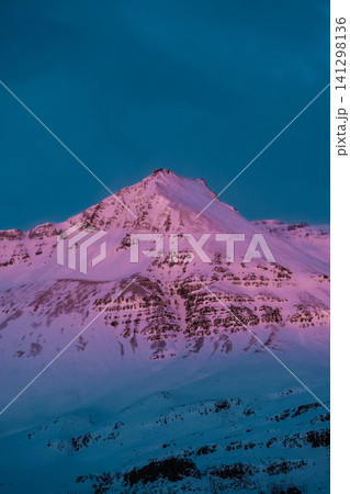 Pink alpenglow illuminates a snow-covered mountain peak in Hornafjordur, south Iceland. Pink alpenglow illuminates a snow-covered mountain peak in Hornafjordur, south Iceland. 141298136