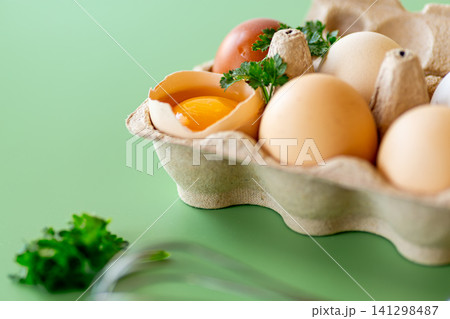Fresh eggs in box with parsley and metal whisk top view Fresh eggs in box with parsley and metal whisk top view 141298487