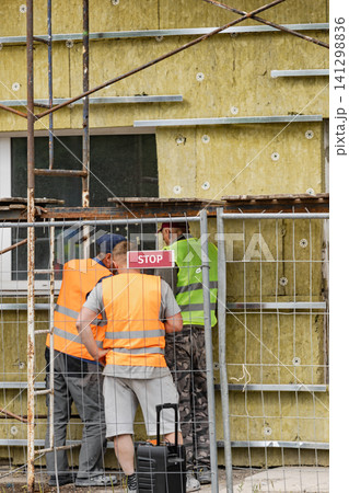 Workers are engaged in the process of installing mineral wool insulation on the exterior of a commercial building. Safety gear is worn by the crew 141298836